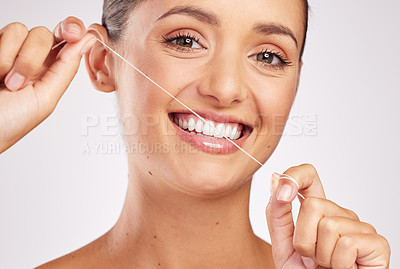 Buy stock photo Shot of an attractive young woman flossing her teeth against a studio background