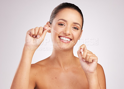 Buy stock photo Shot of an attractive young woman flossing her teeth against a studio background