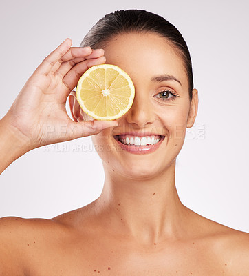 Buy stock photo Shot of an attractive young woman holding a lemon against a studio background