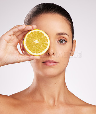 Buy stock photo Shot of an attractive young woman holding an orange against a studio background