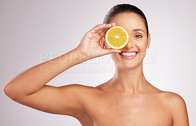 Buy stock photo Shot of an attractive young woman holding an orange against a studio background
