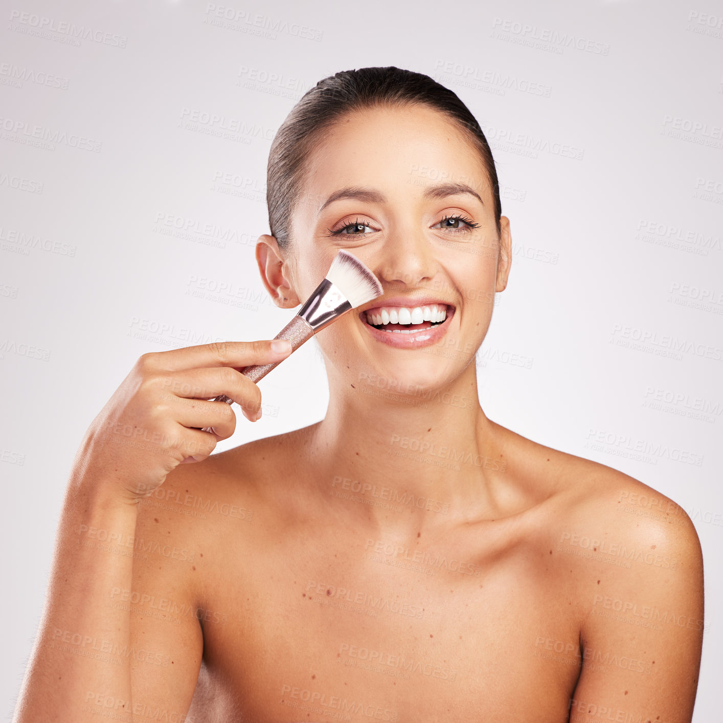 Buy stock photo Shot of an attractive young woman using a makeup brush against a studio background