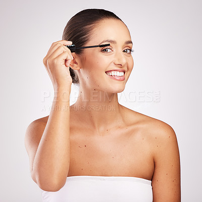 Buy stock photo Shot of an attractive young woman applying mascara against a studio background