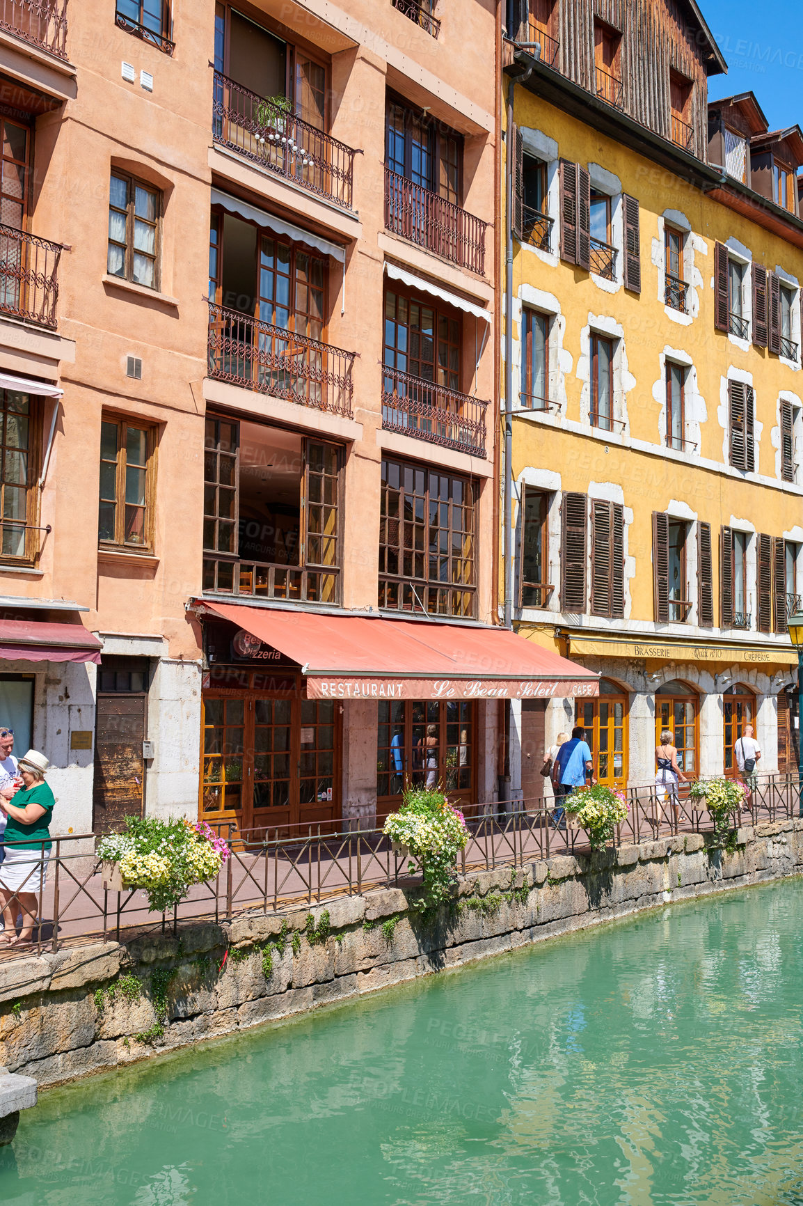 Buy stock photo Building, canal and tourism in city, people and vacation for getaway trip, sunshine and location. Travel, outdoor and buildings with architecture, plants and summer holiday for journey and explore