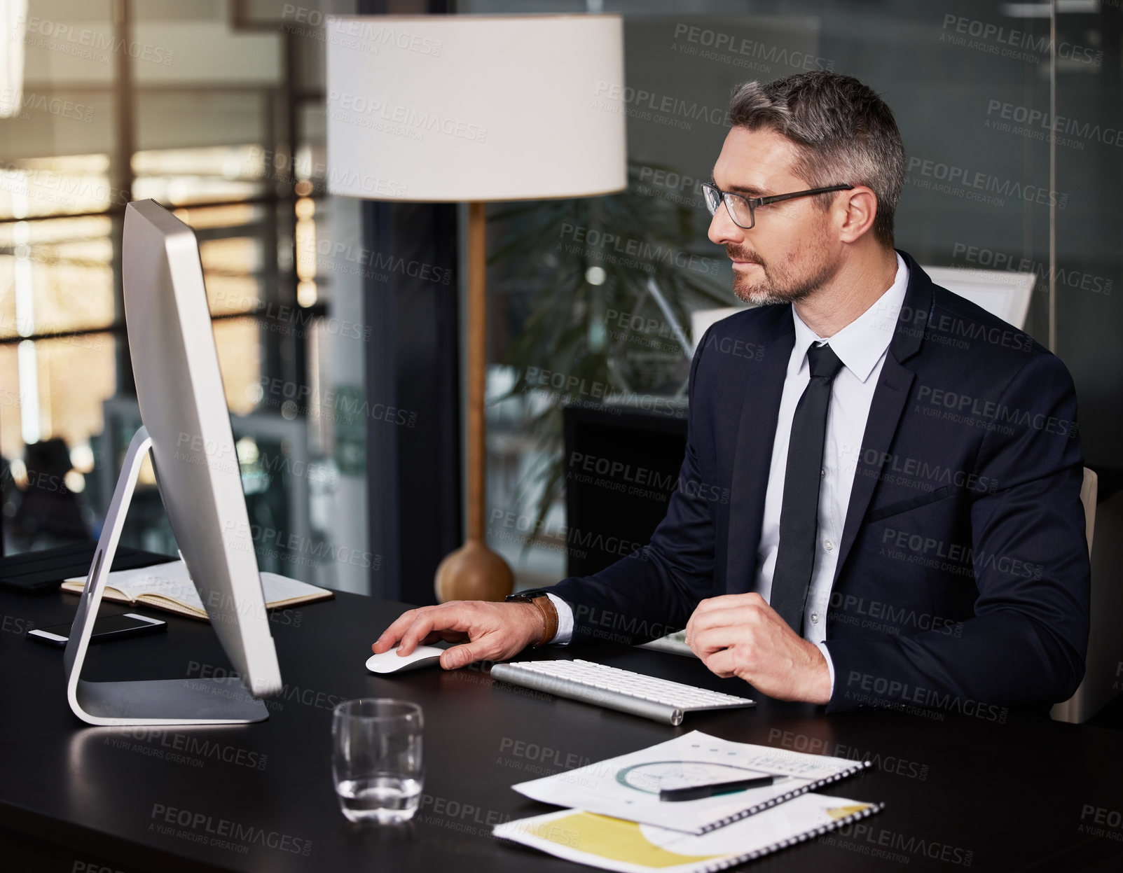 Buy stock photo Shot of a businessman using his computer while sitting at his desk