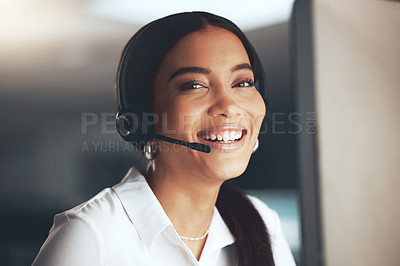 Buy stock photo Shot of a young call centre agent sitting alone in her office and using her computer
