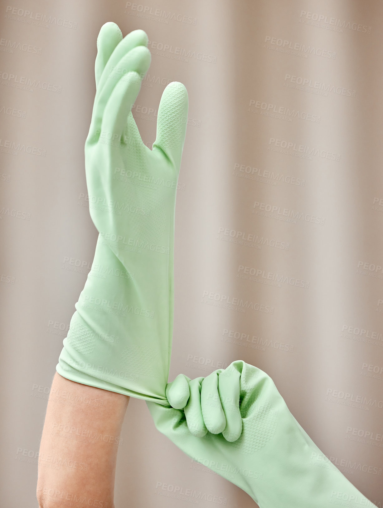 Buy stock photo Shot of an unrecognizable person putting on gloves at home