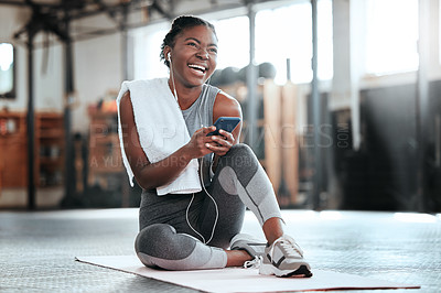 Buy stock photo Phone, earphones and funny black woman in gym for fitness, sports or exercise. Smartphone, music and African female athlete laughing at web meme or comedy on break after workout, training or pilates.