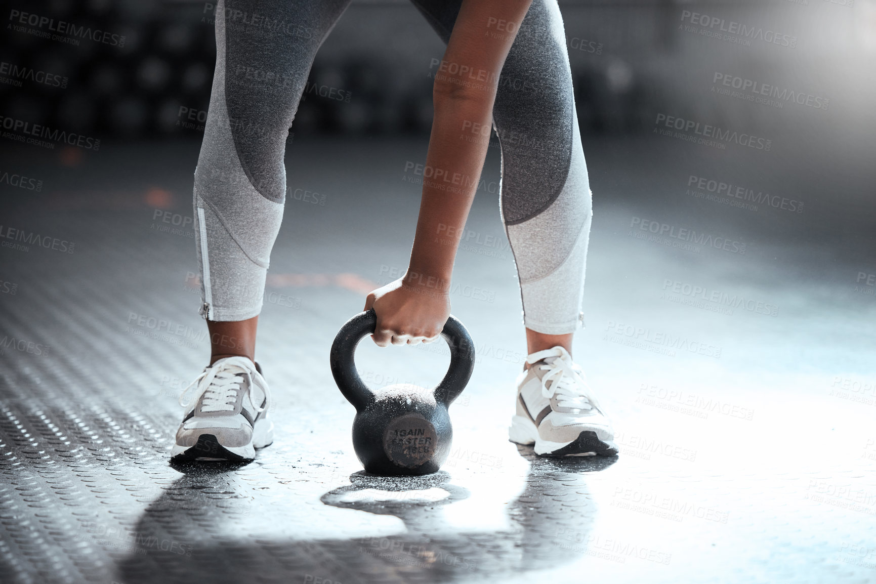 Buy stock photo Cropped shot of an unrecognizable woman lifting a kettlebell at the gym