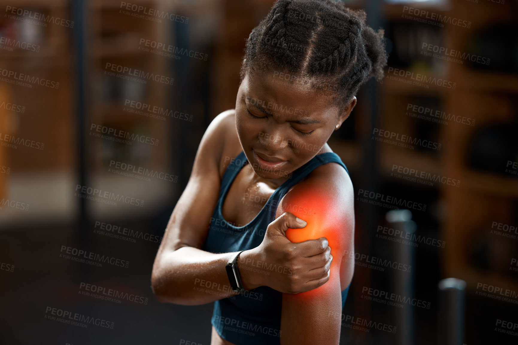 Buy stock photo High angle shot of an attractive and athletic young woman holding her shoulder in pain while at the gym