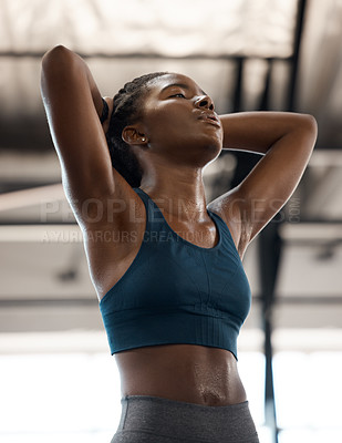 Buy stock photo Low angle shot of an attractive and athletic young woman looking exhausted while standing with her hands behind her head in the gym