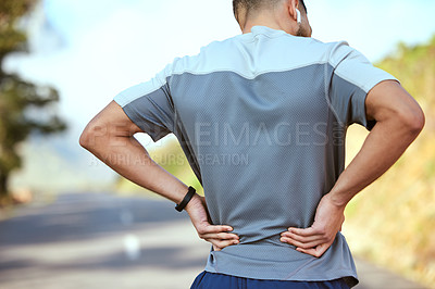 Buy stock photo Rearview shot of an unrecognisable man holding his lower back in pain while exercising outdoors