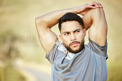 Buy stock photo Shot of a sporty young man stretching his arms while exercising outdoors