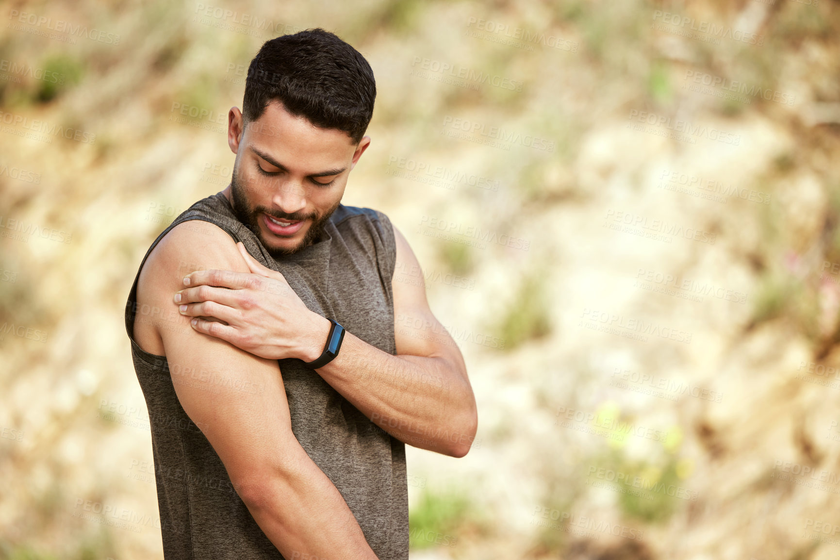 Buy stock photo Shot of a sporty young man holding his shoulder in pain while exercising outdoors