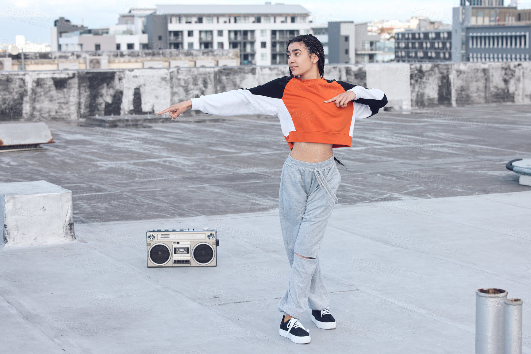 Buy stock photo Shot of a young woman out on a rooftop with a boombox