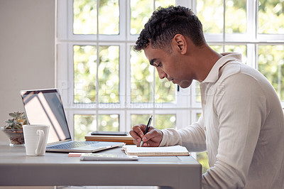 Buy stock photo Shot of an young male writing in his diary at home