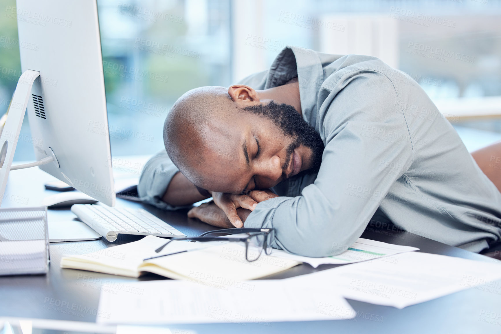 Buy stock photo Shot of a handsome young businessman sleeping on his desk in the office