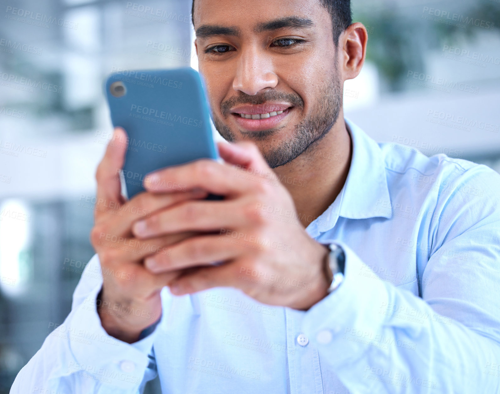 Buy stock photo Shot of a young businessman using his smartphone to send a text message