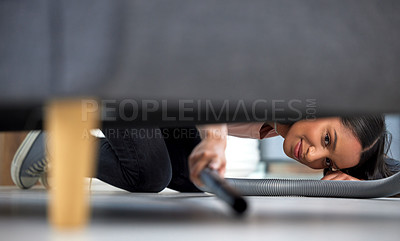 Buy stock photo Shot of a young woman vacuuming under the couch at home