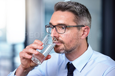 Buy stock photo shot of a mature businessman drinking a glass of water at work