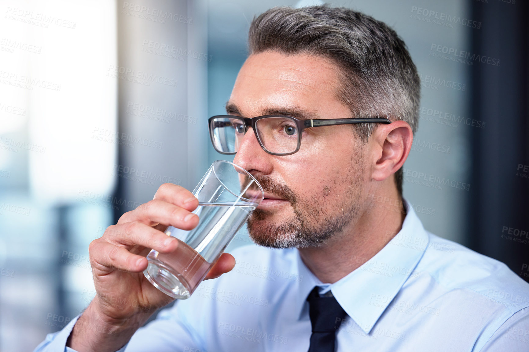 Buy stock photo shot of a mature businessman drinking a glass of water at work