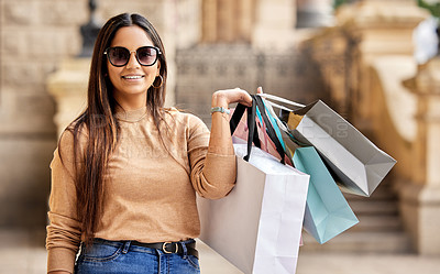 Buy stock photo Cropped portrait of an attractive young woman carrying a bunch of bags while shopping in the city