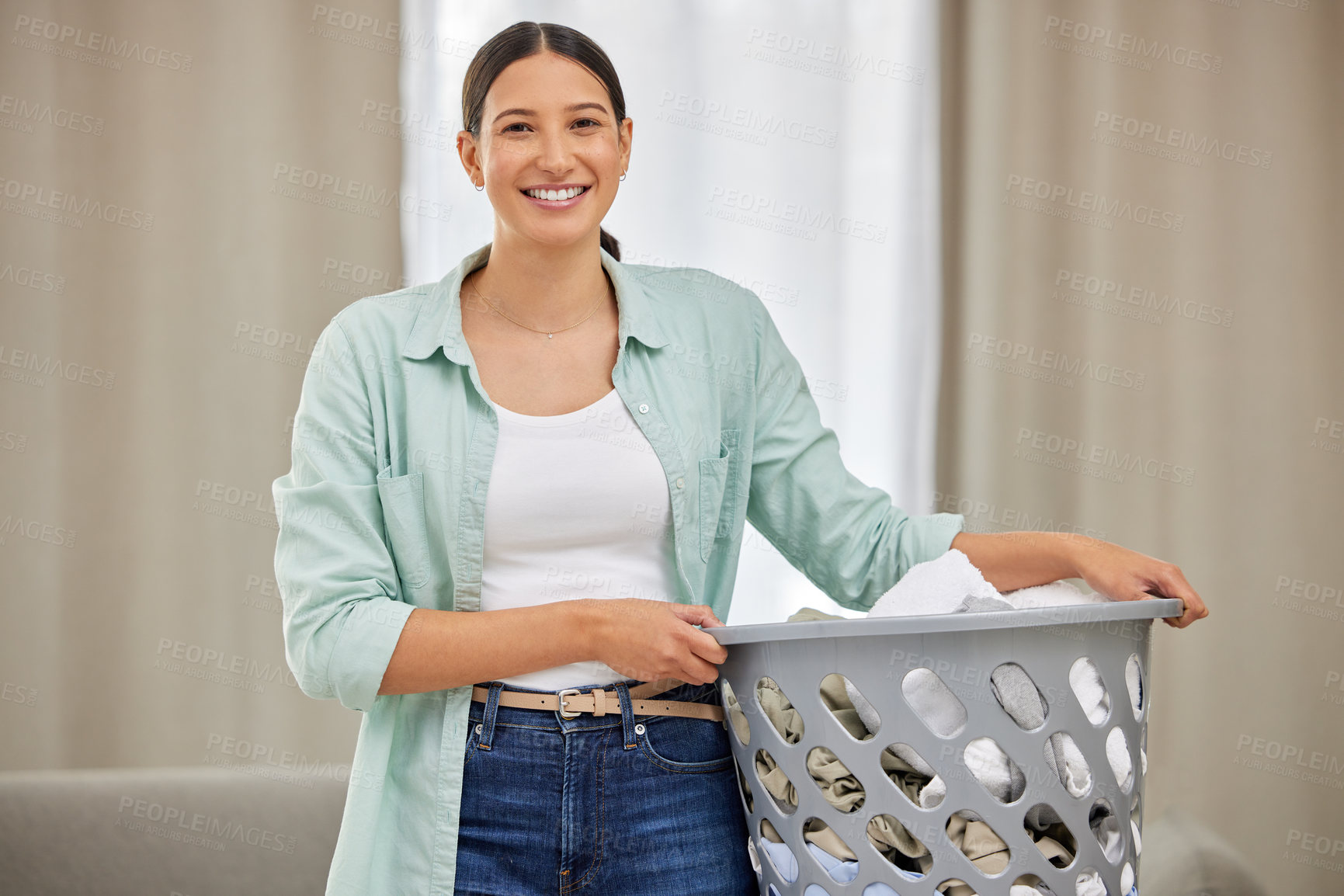 Buy stock photo Shot of a young woman doing laundry at home