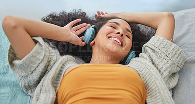 Buy stock photo Shot of a young woman lying down and enjoying the music
