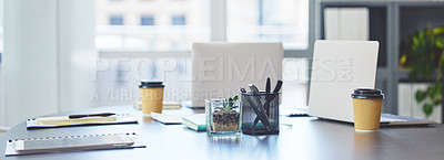 Buy stock photo Shot of technology, takeaway coffee cups and office supplies on a desk in an empty office during the day