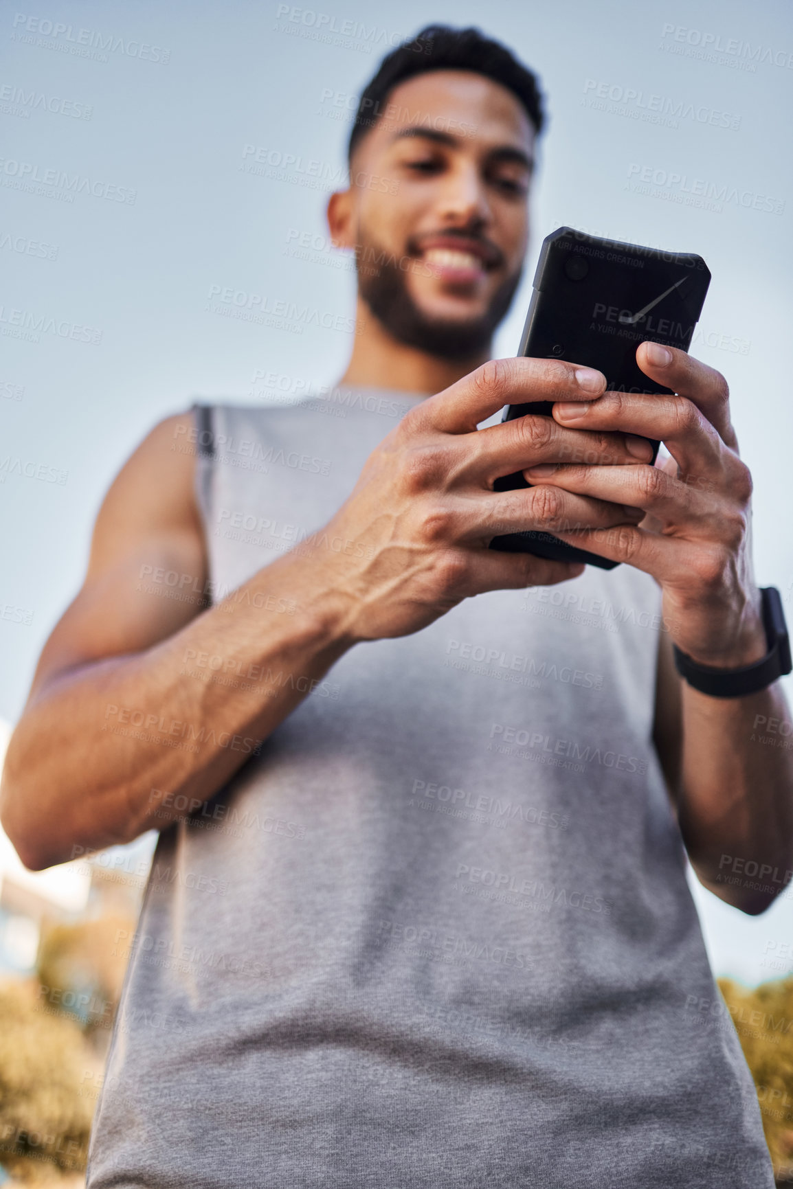 Buy stock photo Fitness, sports and man with phone in hands, checking health app, social media or workout tracker online. Smile, wellness and male athlete with cellphone to check digital exercise schedule in park.