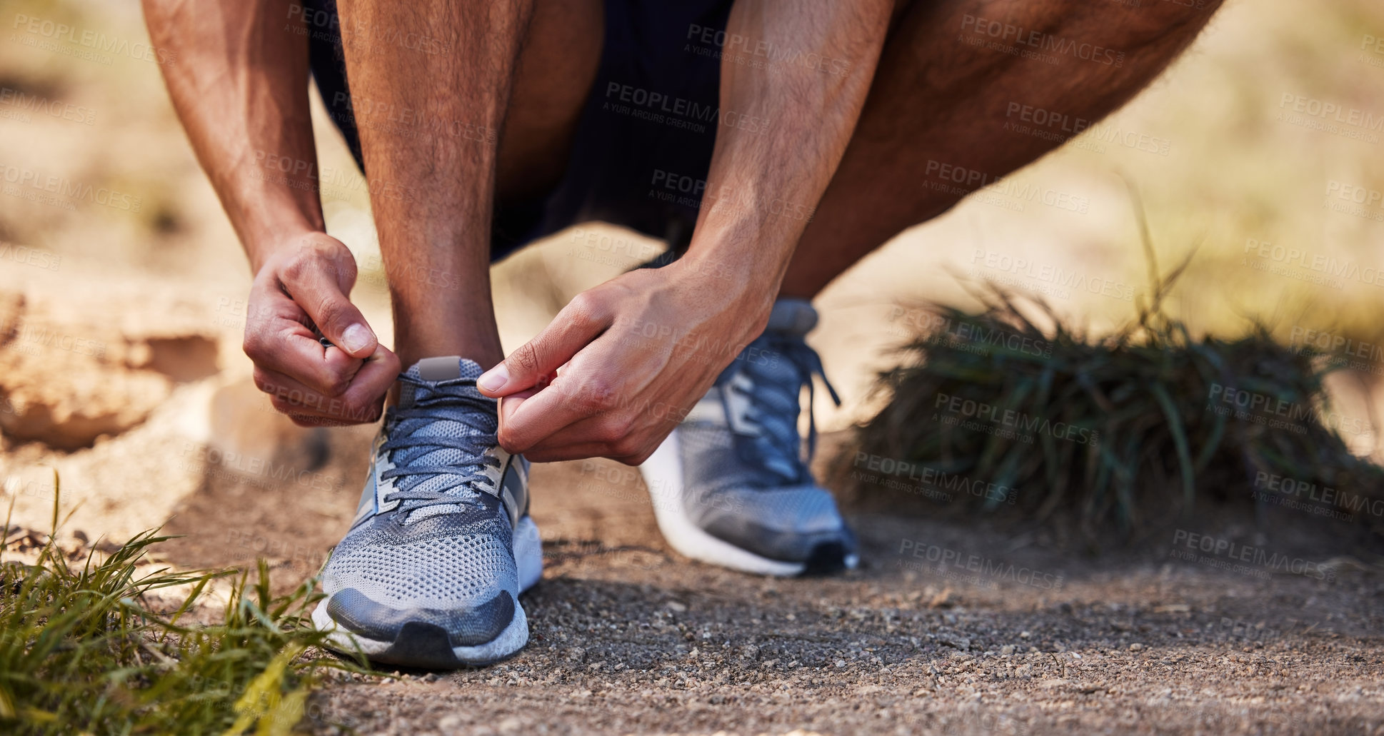 Buy stock photo Cropped shot of an unrecognizable man crouching down to tie his shoelaces before going on an outdoor run