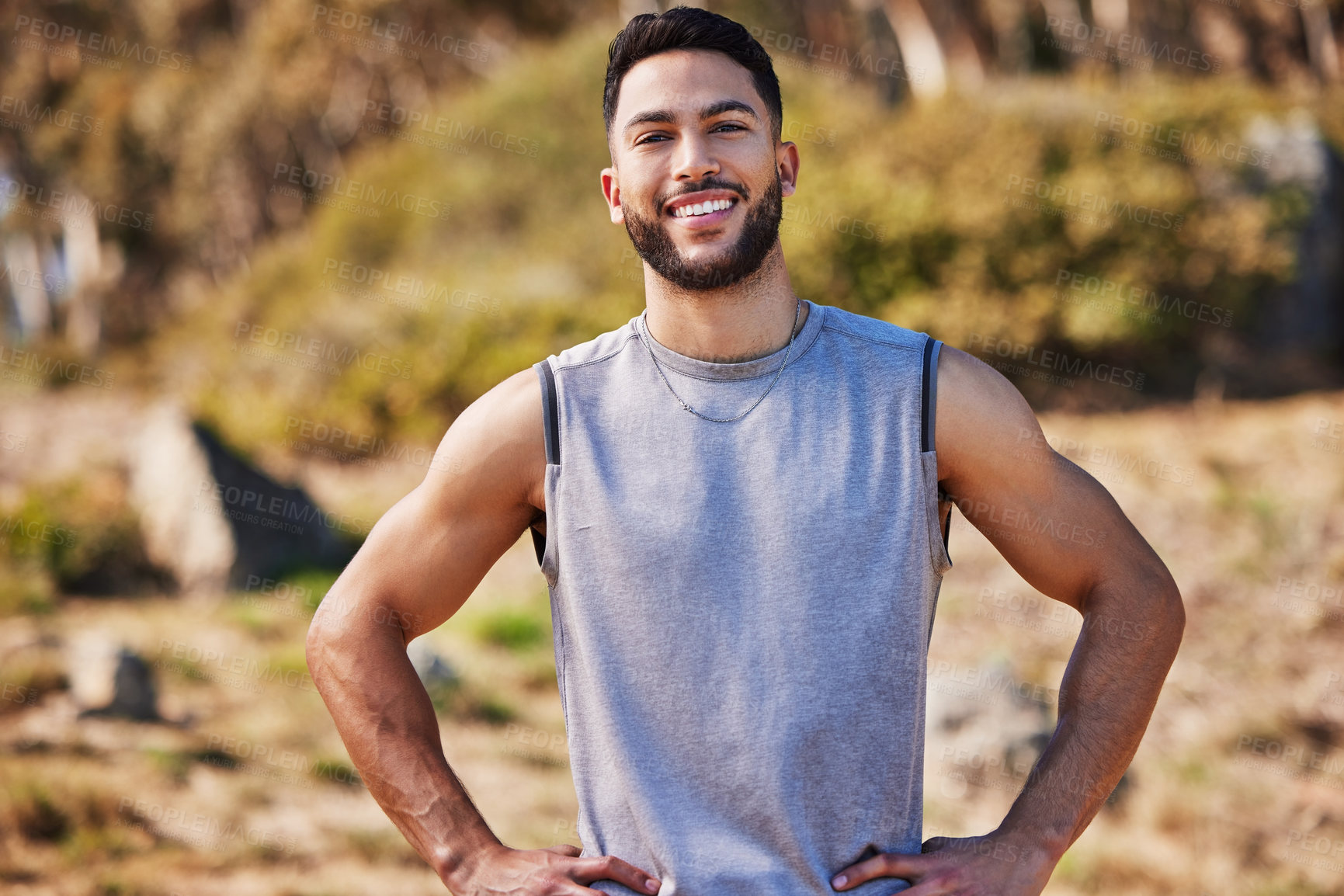 Buy stock photo Shot of a handsome young man standing alone outside with his hands on his hips after a run