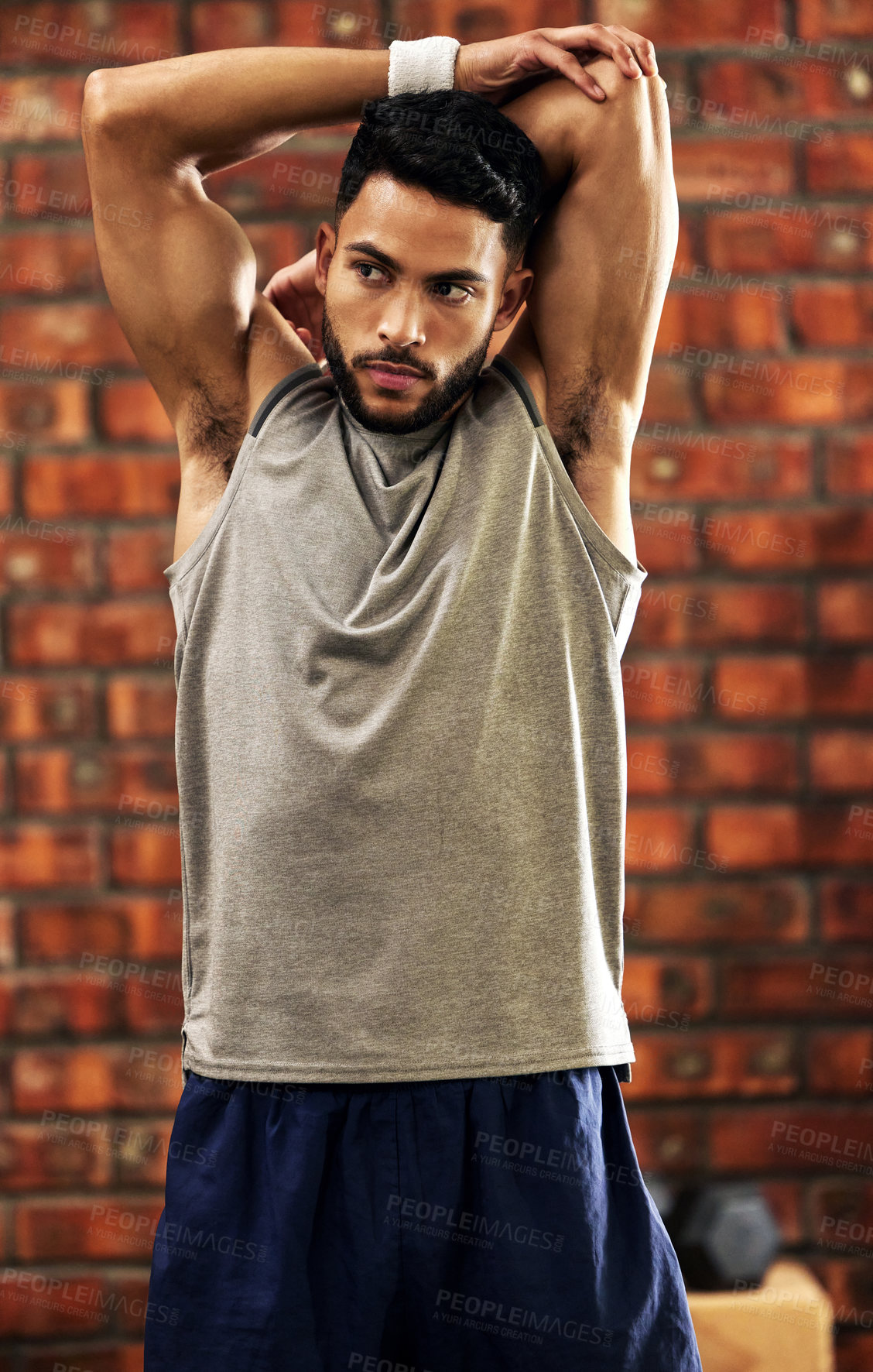 Buy stock photo Shot of a young man stretching before his workout in the gym
