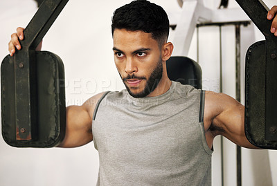 Buy stock photo Shot of a young man working out with a chest press in a gym