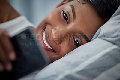 Buy stock photo Bed, girl and phone for dating app, morning and relax on pillow, reading and smile for post online. Weekend, internet and mobile for Indian person, happy and chat with text and connection in home