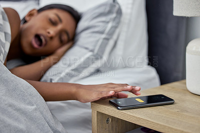 Buy stock photo Shot of a woman's alarm on her cellphone going off while she lies in bed