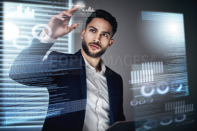 Buy stock photo Shot of a handsome young businessman standing alone in the office at night and using an interactive screen