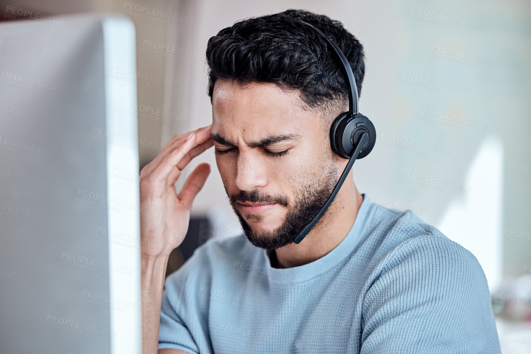 Buy stock photo Shot of a young businessman working in a call center experiencing a headache