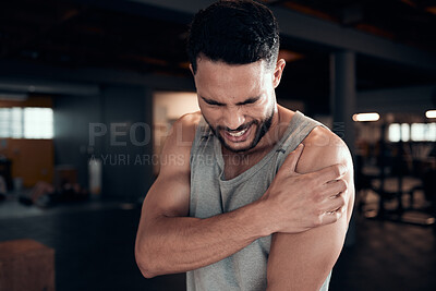 Buy stock photo Shot of a young man experiencing arm pain in the gym