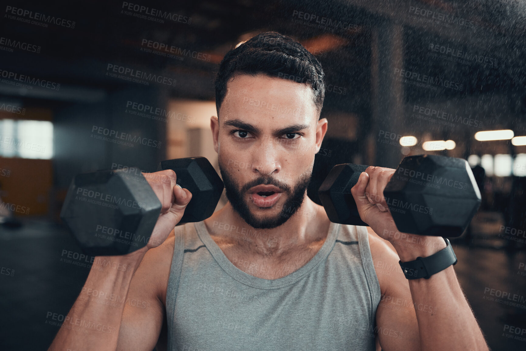 Buy stock photo Shot of a young man using weights in the gym