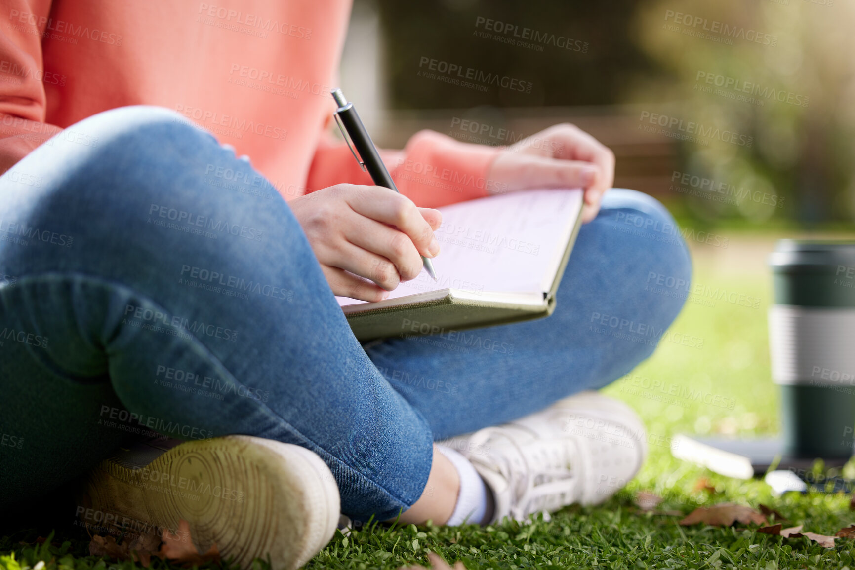 Buy stock photo Shot of a student writing in her notebook while sitting outside