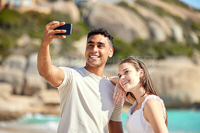 Buy stock photo Shot of a young couple taking selfies at the beach