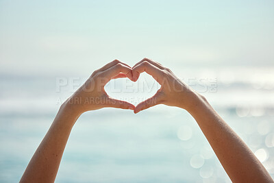 Buy stock photo Shot of two unrecognizable people making a heart gesture with their hands at the beach