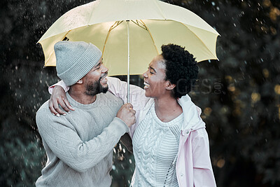 Buy stock photo Shot of a young couple standing under an umbrella
