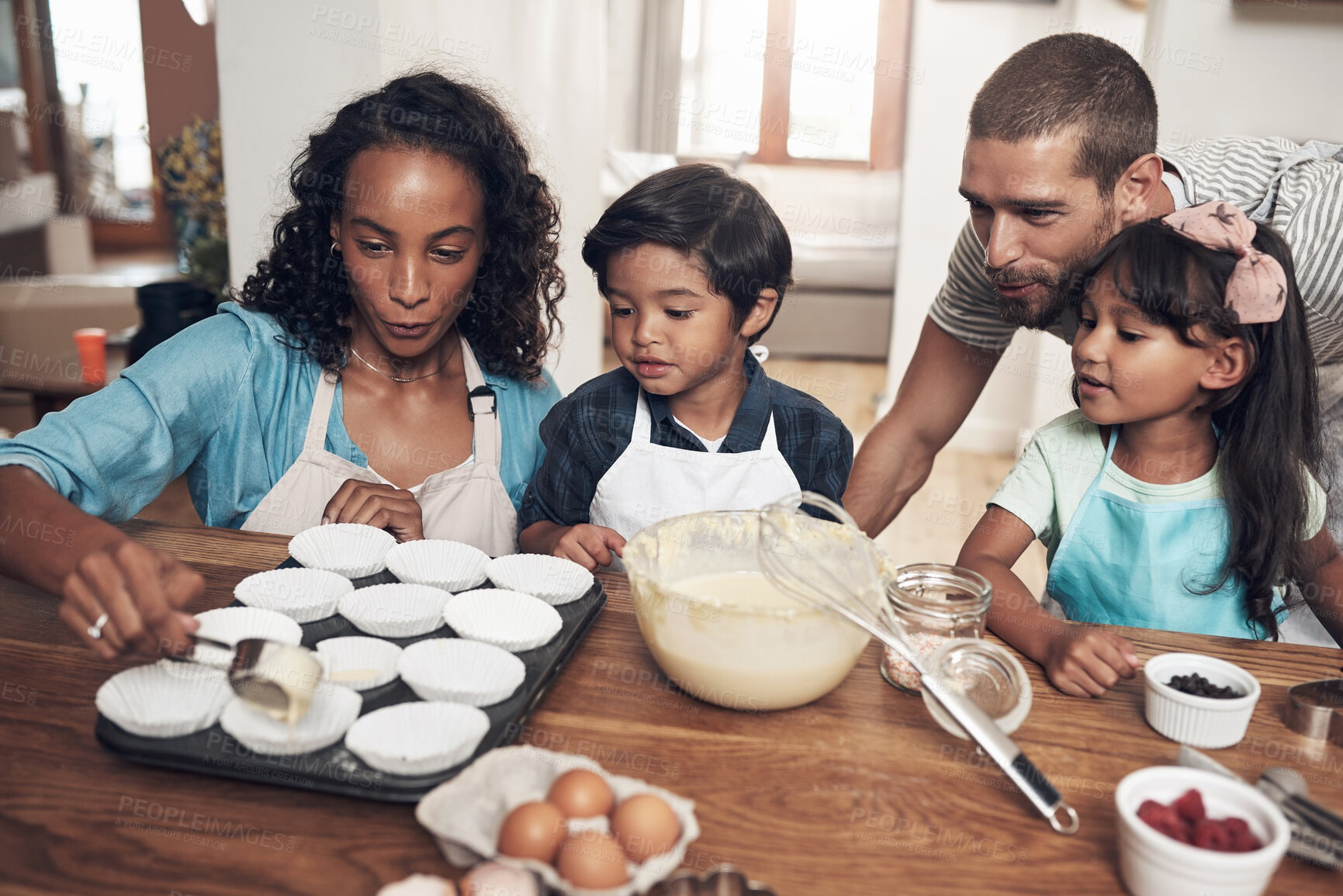 Buy stock photo Shot of a young couple baking at home with their two children