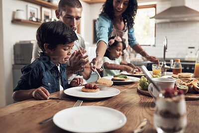 Buy stock photo Shot of a little boy smiling at the table with his family in the background