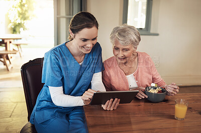 Buy stock photo Shot of a young nurse and senior woman using a digital tablet at breakfast time in a nursing home