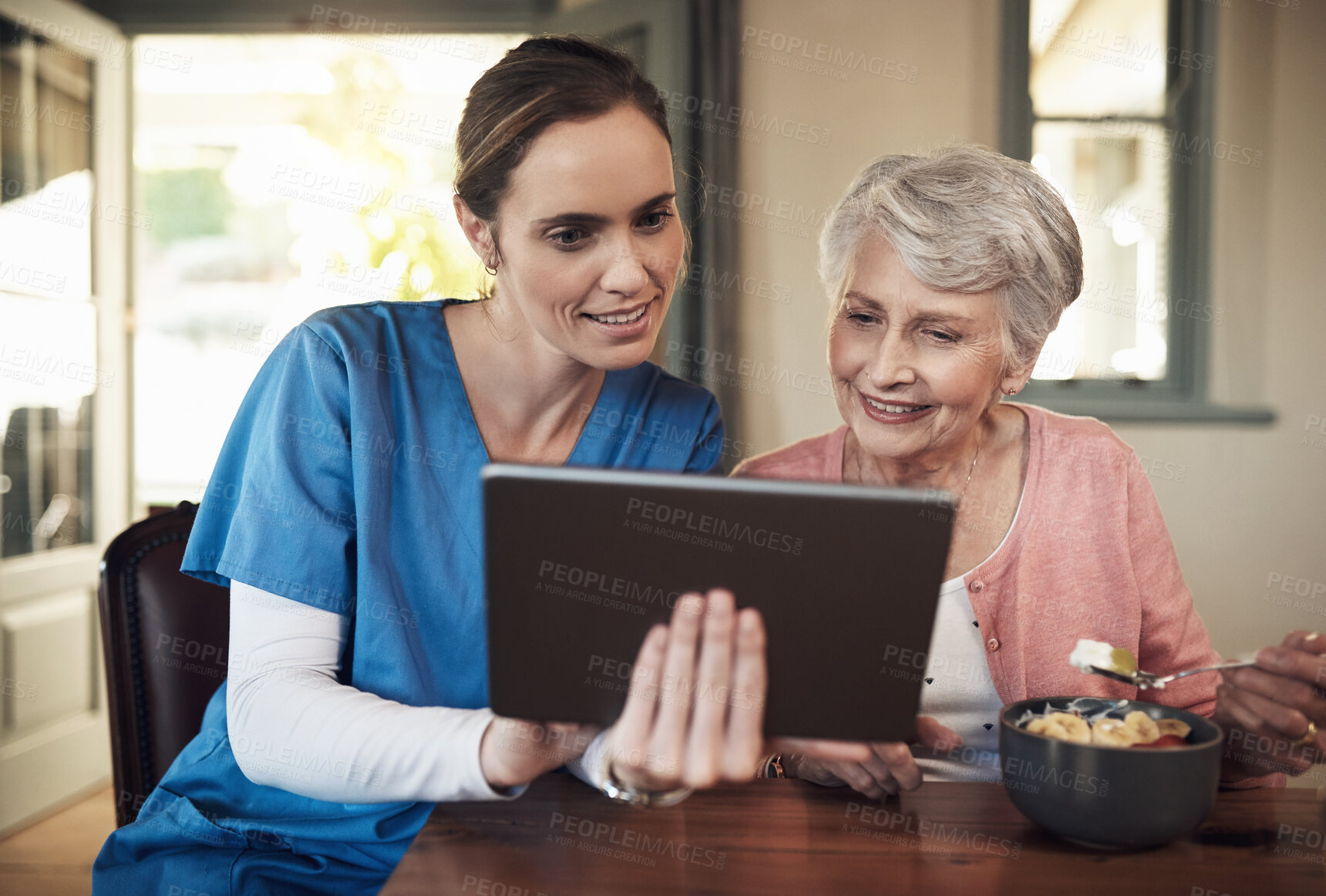 Buy stock photo Shot of a young nurse and senior woman using a digital tablet at breakfast time in a nursing home