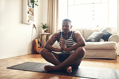 Buy stock photo Shot of a sporty young man meditating at home