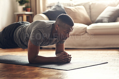 Buy stock photo Shot of a sporty young man doing plank exercises at home